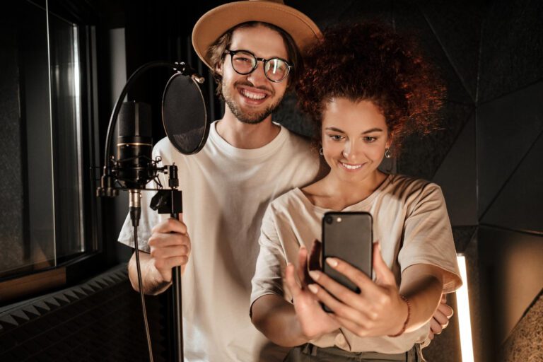 couple-attractive-stylish-singers-happily-taking-selfie-together-smartphone-modern-sound-recording-studio
