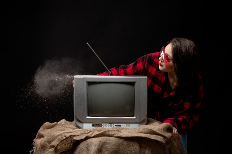 front-view-young-beautiful-lady-checkered-red-black-shirt-red-sunglasses-near-little-tv-blowing-out-dust