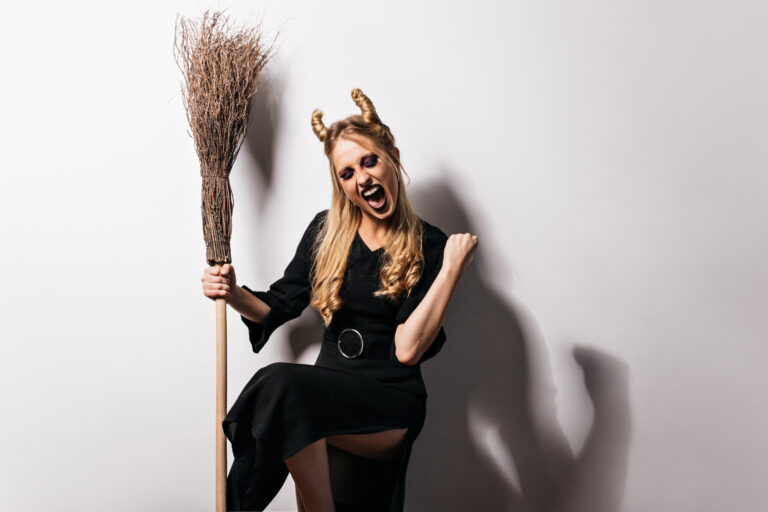 Excited blonde witch posing with broom