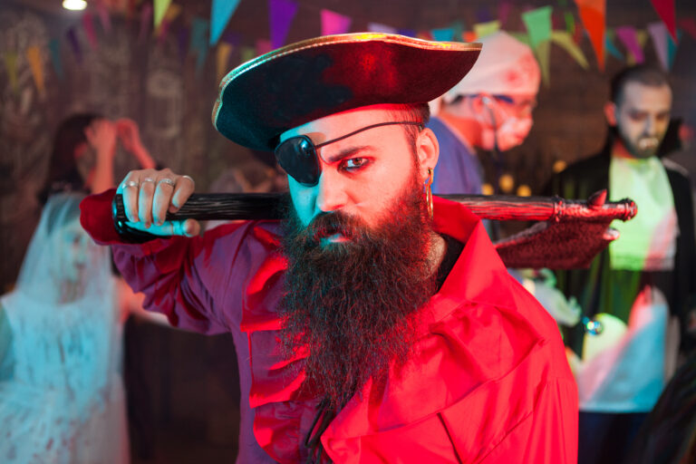 Side view portrait of handsome bearded man in a pirate costume at halloween celebration